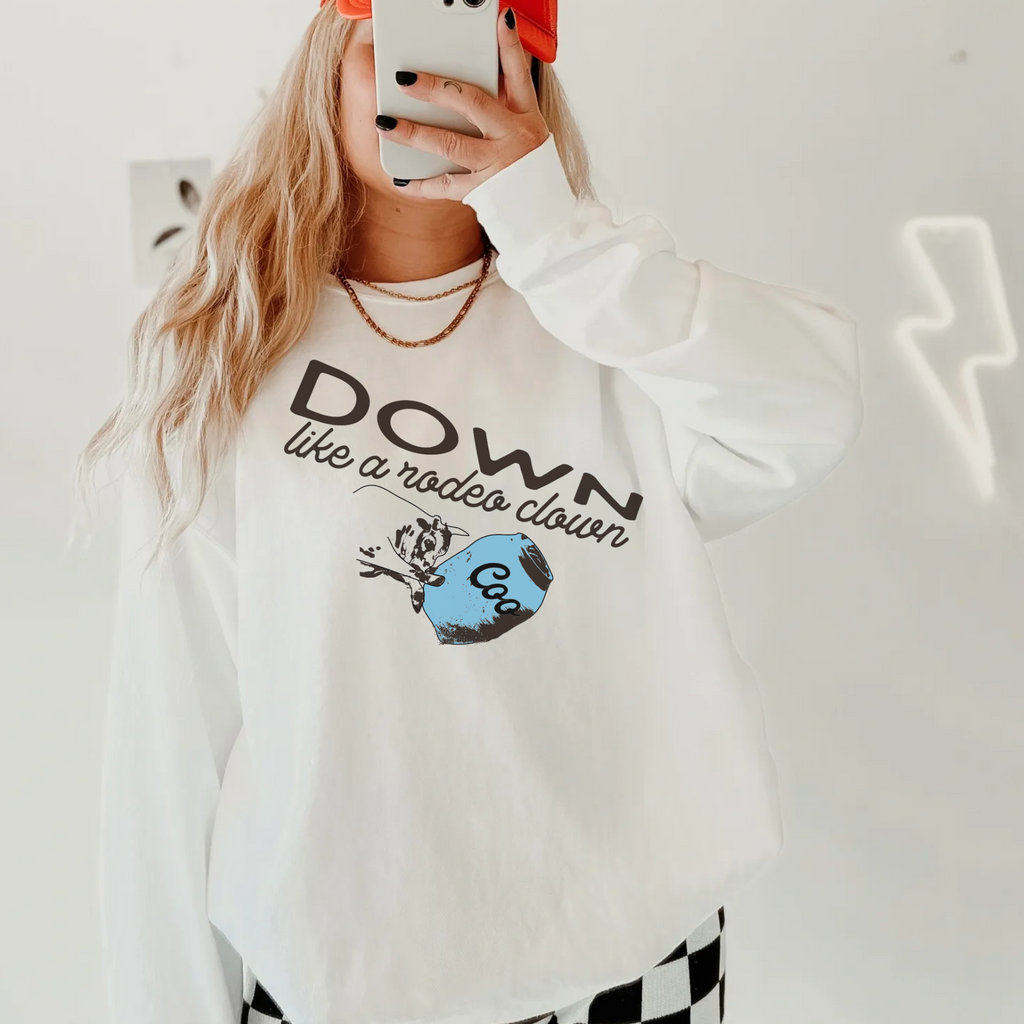 a woman wearing a white sweater that says down like a rodeo clown