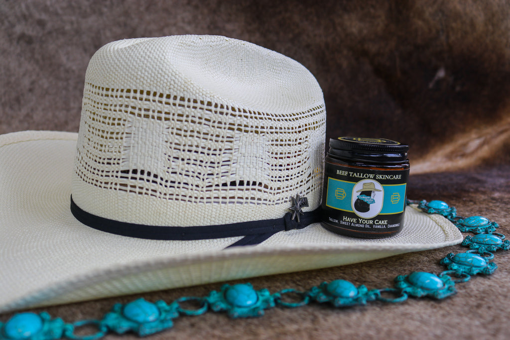White straw hat with black band and jar of cream on a brown surface