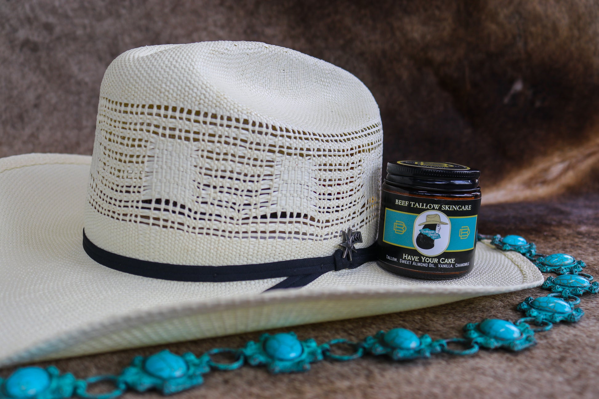 White straw hat with black band and jar of cream on a brown surface